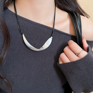Detail of silver irregular metal pendant with brushed texture on black cord necklace