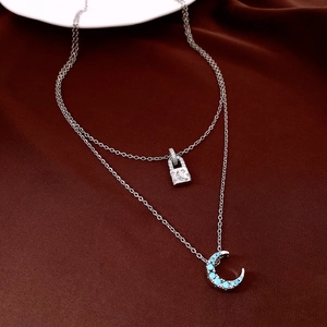Détail d'un collier double en argent avec un cadenas en zircon et un pendentif lune bleue