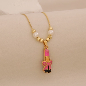 Gold lipstick pendant necklace with pink enamel bow and white pearls on stone background