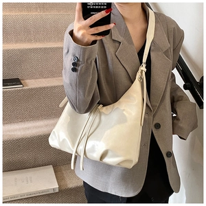 Detail of cream white pleated shoulder bag with soft glossy finish and drawstring design