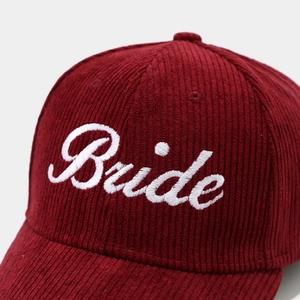 Close-up of Bride script embroidery on burgundy corduroy baseball cap with vintage texture