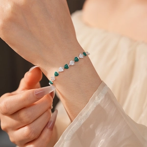 Macro detail of French vintage bracelet featuring green zircon hearts and silver links