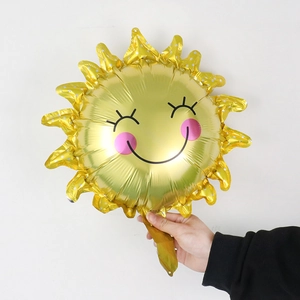 Close-up of golden sun-shaped foil balloon with smiling face for birthday party