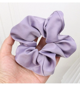 Detail of light purple satin scrunchie showing smooth texture and elastic design