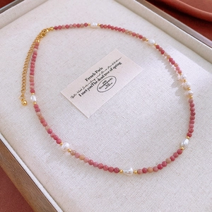 Detail of beaded bracelet with red rhodochrosite stones, baroque pearls and golden lobster clasp