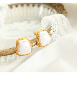 Macro detail of vintage gold twisted earrings with elegant iridescent pearl-like inserts