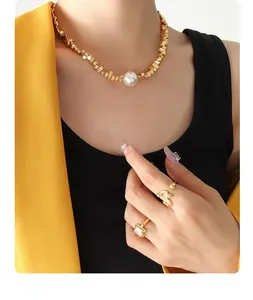 Primer plano de collar de perlas y anillos dorados con una chaqueta amarilla