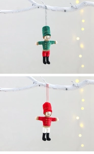 Close-up of red and green nutcracker soldier plush ornaments hanging on white branches