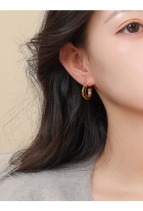 Close-up of 14k gold plated hoop earring with leopard print on a model's ear