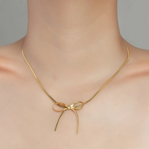 Elegante collana con ciondolo a fiocco d'oro su catena a serpente indossata da donna