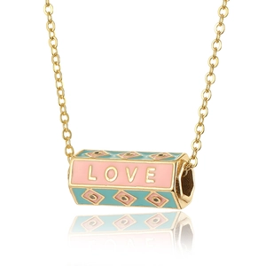 Macro shot of gold cylinder pendant with LOVE text and colorful enamel inlay details