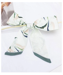 Detail of floral pattern silk scarf tied in a bow with green and blue botanical design