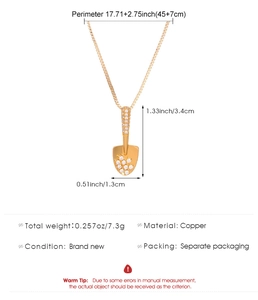 Macro detail of gold shovel pendant necklace showing size 34x13mm and 45+7cm chain length