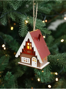 Wooden Christmas LED cottage hanging on a tree with warm glowing lights
