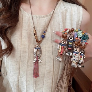 Macro detail of hand-painted fish ceramic pendant with ethnic wood beads and tassel