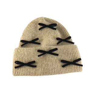 Beige rabbit fur knit beanie for women with black bow details and ear protection