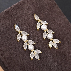 Macro-opname van gouden bloemenoorbellen met marquise zirkoon en elegante witte parels