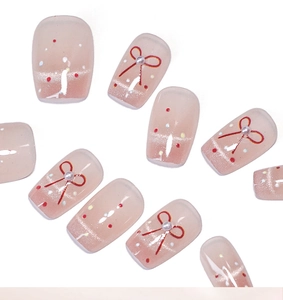 Détail de faux ongles œil de chat roses avec nœuds rouges peints et perles