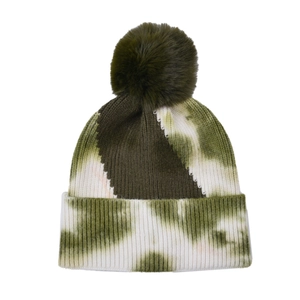 Detailed view of tie-dye knit beanie texture with olive green faux fur pom-pom