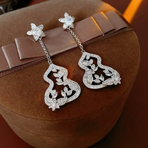Macro detail of silver gourd earrings with cubic zirconia on brown velvet box