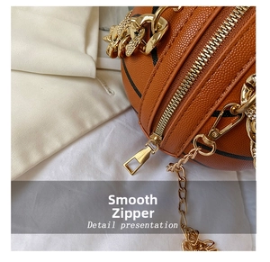 Detailed close-up of smooth gold metal zipper and chain on brown basketball round bag