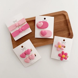 Pink heart and bow hair clips set for girls displayed on a natural wooden tray