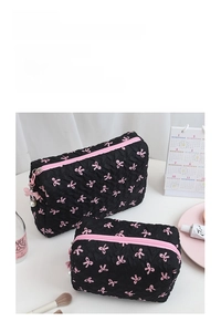 Detailed view of black pleated cosmetic bags with pink bows and pearl zipper charms