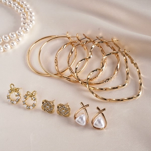 Vue détaillée d'un ensemble de boucles d'oreilles dorées avec perles et strass sur soie