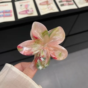 Détail d'une pince à cheveux fleurie marbrée rose et verte avec effet translucide