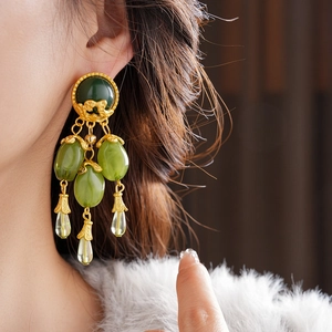Close-up of vintage gold tassel earrings with olive green stone and clear drop pendants