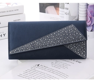 Macro shot of navy blue satin clutch bag with sparkling rhinestone detail and V-flap