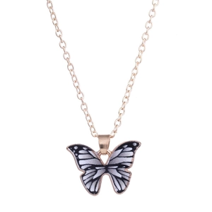 Macro detail of enamel butterfly pendant with gold-plated edges on a thin gold chain necklace