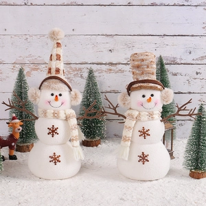 Two plush Christmas snowmen with beige plaid hats and scarves on festive snow background
