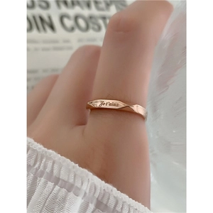 Textured gold ring with Je t'aime engraving shown on a hand with white fabric
