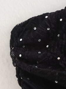 Gros plan sur de la dentelle noire avec strass argentés brillants sur détail du vêtement