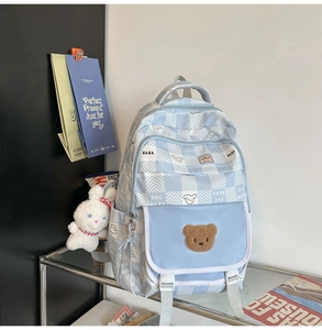 Close-up of cute light blue plaid backpack with plush bear patch and bunny pendant