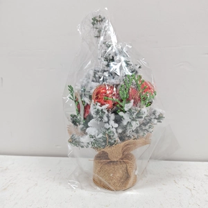 Detailed view of mini Christmas tree with red baubles, artificial snow, and burlap base