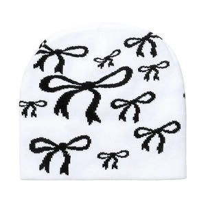Detailed view of the soft knitted texture and black bow pattern on the white beanie