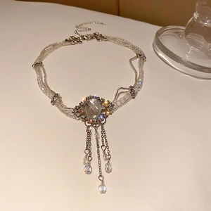 Détail d'un collier à pompons argenté orné de strass et de perles de cristal
