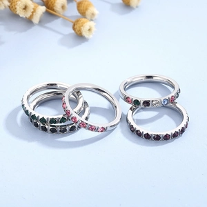 Detail of five titanium steel rings set with colorful cubic zirconia on a blue background