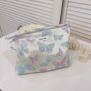 Floral butterfly jacquard canvas makeup bag with simple wish label on white marble surface
