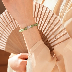 Detail of green chalcedony beaded bracelet with silver fish charm on model wrist
