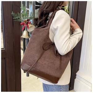 Close-up of dark brown suede tote bag with leather straps on model's shoulder