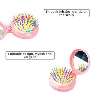 Dettaglio della spazzola per capelli pieghevole rosa con setole colorate e specchio