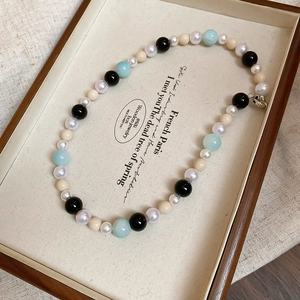 Detailed macro view of mixed pearl and glass beads on a minimalist collar necklace