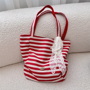 Detail of red and white striped canvas tote featuring a decorative white lace bow