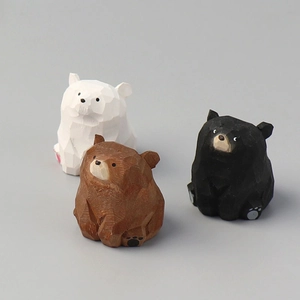 Detailed view of three handcrafted wooden bears in white brown and black with geometric carving