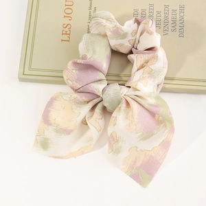 Floral chiffon bow scrunchie with long ribbons displayed on a vintage French book