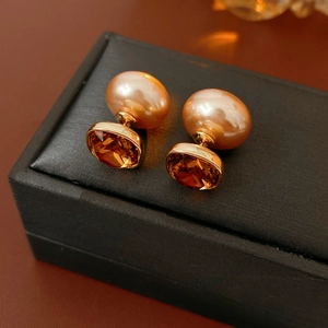 Dettaglio di orecchini con perle champagne e gemma ambra in oro su portagioie elegante