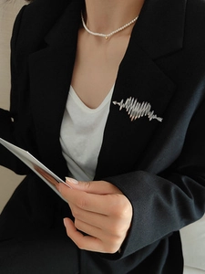 Close-up of silver heartbeat wave brooch pinned on a black suit lapel for elegant styling